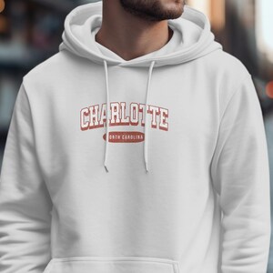 White hoodie with "Charlotte North Carolina" text on chest.