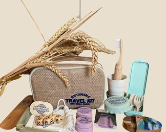 May include: A sustainable travel kit featuring a tan burlap zippered bag with the text SUSTAINABLE TRAVEL KIT, a bamboo toothbrush, a light green cutlery case, a wooden comb, two purple containers, a pill case, dice, and a small wooden tray.