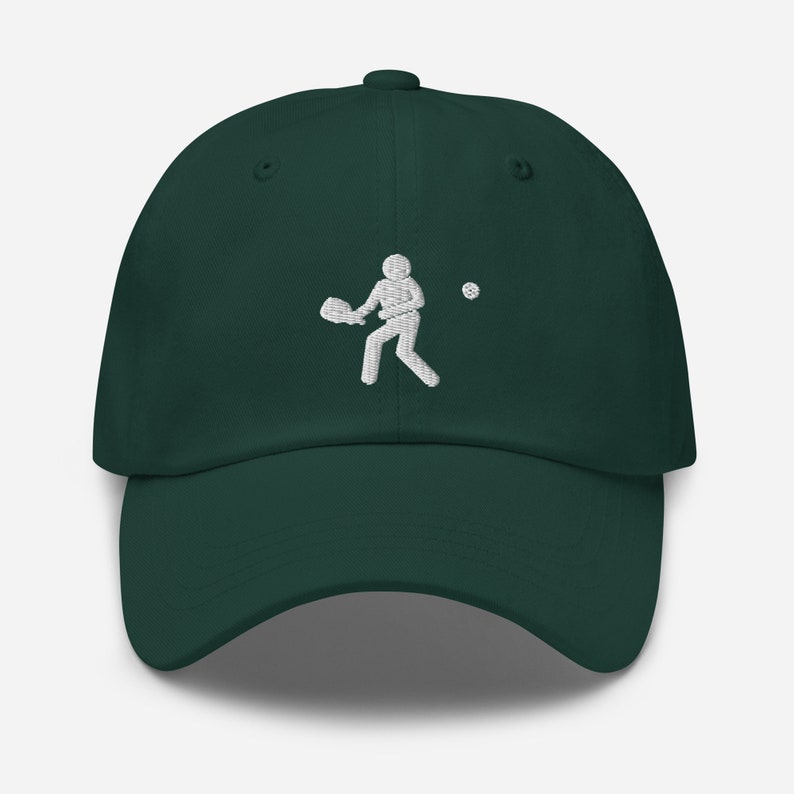 Puede incluir: Una gorra de b&eacute;isbol verde oscuro con una imagen bordada en blanco de una persona jugando un deporte con una raqueta y una pelota.