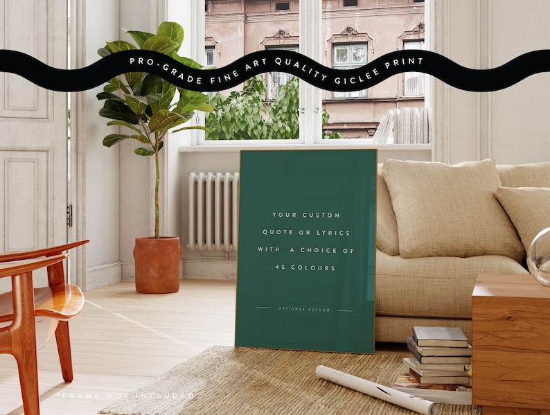K&ouml;nnte beinhalten: Ein gerahmter Kunstdruck mit tealfarbenem Hintergrund zeigt den Text: "YOUR CUSTOM QUOTE OR LYRICS WITH A CHOICE OF 45 COLOURS." Der Druck befindet sich in einem Raum mit Sofa, Pflanze und Holzstuhl. Der Text "PRO-GRADE FINE ART QUALITY GICLEE PRINT" steht oben.