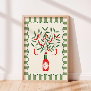 May include: A framed art print featuring a stylized illustration of a red chili pepper plant. The plant sprouts from a red bottle labeled "CHILLI" against a cream background with a green and white striped border. The frame is light brown.