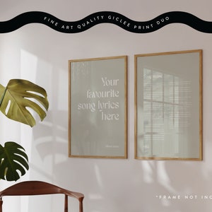May include: A gicl&eacute;e print duo featuring two framed artworks. One displays the text "Your favourite song lyrics here", the other contains song lyrics. Both are in light-colored frames, with a plant and chair in the foreground.