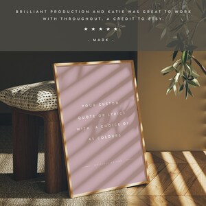 K&ouml;nnte beinhalten: Ein gerahmter Druck mit goldenem Rand, der den Text "YOUR CUSTOM QUOTE OR LYRICS WITH A CHOICE OF 45 COLOURS" zeigt. Der Druck ist in einem zarten Rosa gehalten und lehnt an einem Holzschemel. Der Text "BRILLIANT PRODUCTION AND KATIE WAS GREAT TO WORK WITH THROUGHOUT. A CREDIT TO ETSY." steht oben.