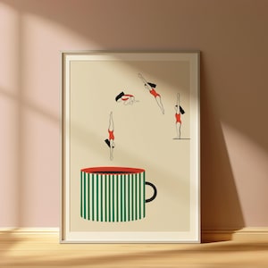 May include: Art print featuring a large coffee cup with green and white stripes and a red rim. Above the cup, stylized figures in red swimsuits are depicted diving and floating, creating a whimsical scene. The artwork is framed.
