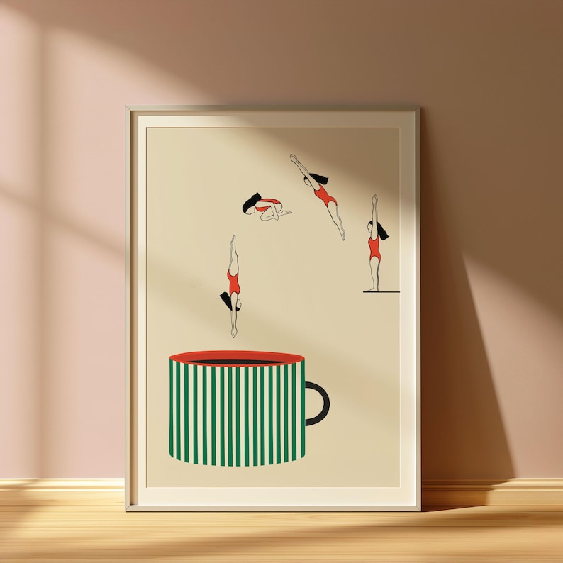 May include: Art print featuring a large coffee cup with green and white stripes and a red rim. Above the cup, stylized figures in red swimsuits are depicted diving and floating, creating a whimsical scene. The artwork is framed.