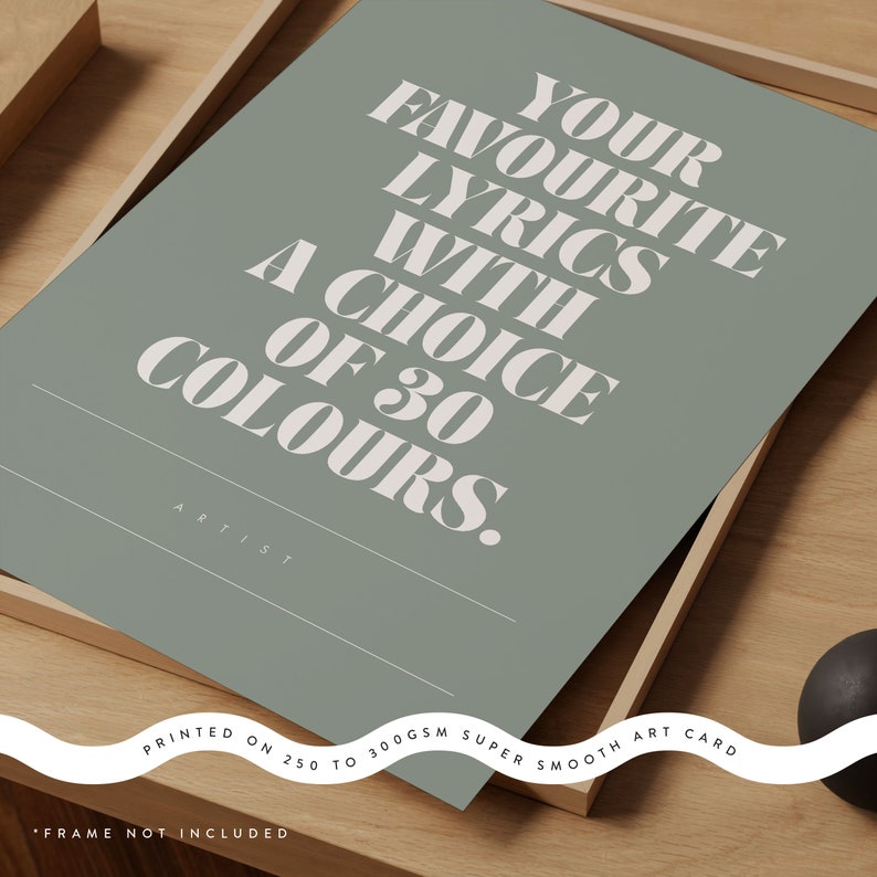 May include: A sage green art print with the text "YOUR FAVOURITE LYRICS WITH A CHOICE OF 30 COLOURS." The print is on a super smooth art card and is displayed in a wooden frame. The text "ARTIST" is also visible.