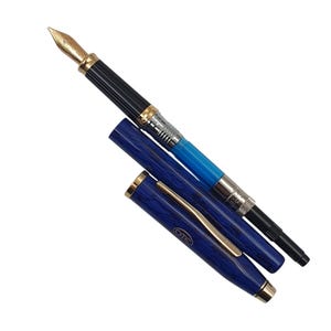 K&ouml;nnte beinhalten: Ein F&uuml;llfederhalter mit goldener Feder, schwarzen und silbernen Akzenten und einem blau gemusterten Schaft. Die Kappe ist ge&ouml;ffnet und zeigt die Tintenpatrone. Schreibger&auml;t.