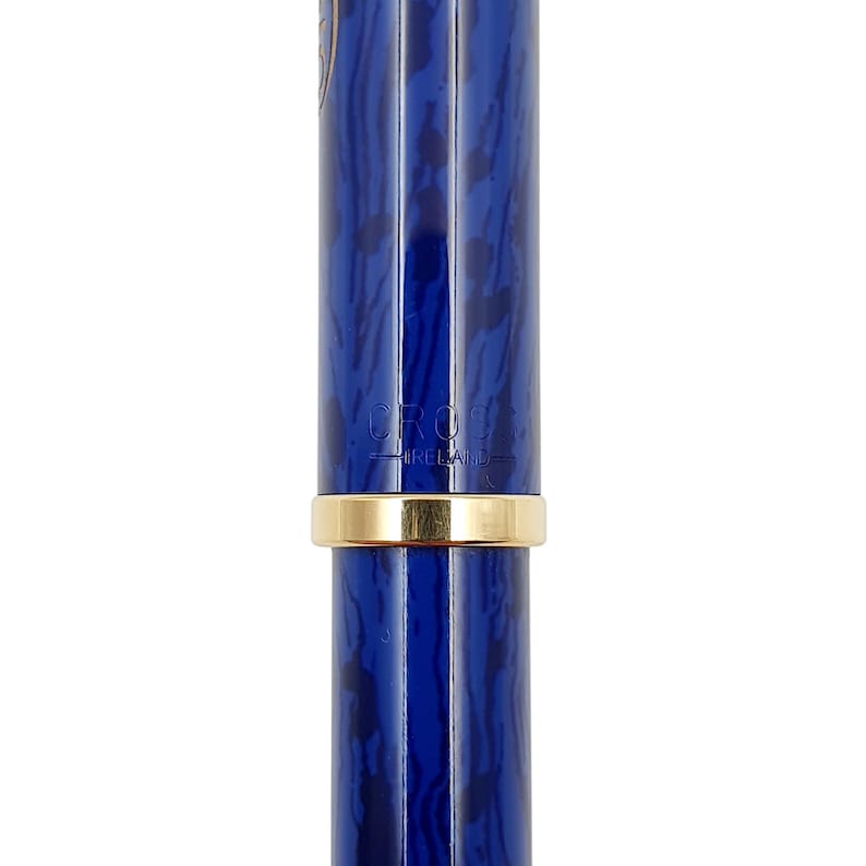 K&ouml;nnte beinhalten: Nahaufnahme eines blauen Stifts mit Marmormuster und einem goldfarbenen Band. Auf dem Stift stehen die W&ouml;rter "CROSS" und "IRELAND". Der Stift ist ein Schreibger&auml;t.