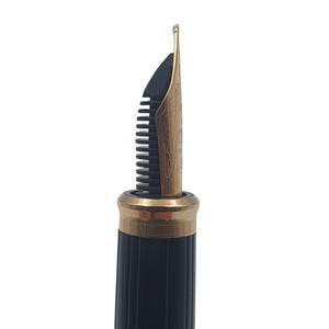 K&ouml;nnte beinhalten: Nahaufnahme einer Feder eines F&uuml;llfederhalters. Die Feder ist goldfarben mit aufwendigen Gravuren und einer schwarzen Zufuhr. Der Stiftk&ouml;rper ist schwarz mit einem goldfarbenen Band in der N&auml;he der Feder.