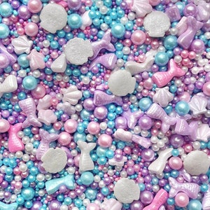 May include: A selection of pastel-coloured sprinkles, including pearls, stars, seashells, and mermaids, ideal for decorating cakes, cupcakes, and other treats.