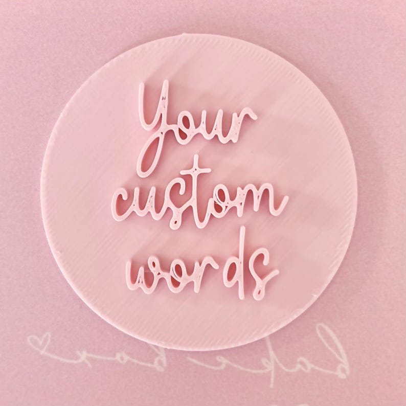 May include: A light pink circular sign with the words "Your custom words" in a cursive font. The sign is on a light pink background. The sign is likely a custom product.