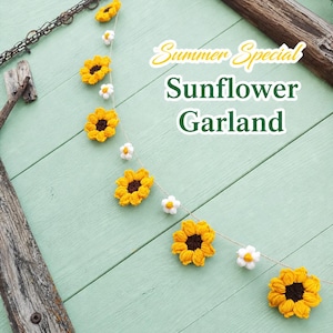May include: A handmade sunflower garland with yellow and brown crochet sunflowers and white daisy accents. The garland is strung on a natural twine and is displayed on a light green wooden surface. Text reads "Summer Special Sunflower Garland."
