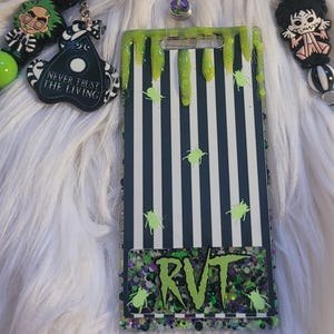 May include: A set of accessories including a badge reel with a coffee cup design, a vertical ID badge holder with black and white stripes and green slime accents, and two beaded keychains featuring character figures and a Never Trust The Living charm.