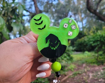 May include: Green glitter Mickey Mouse shaped badge holder with a black silhouette of the Nightmare Before Christmas character Jack Skellington. The badge holder has a green and black beaded lanyard with a clear plastic badge clip.