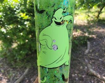 May include: A green tumbler with a green glitter design and a character from the Nightmare Before Christmas, the ghost with the most, printed on the side. The tumbler has a black lid and a clear straw.