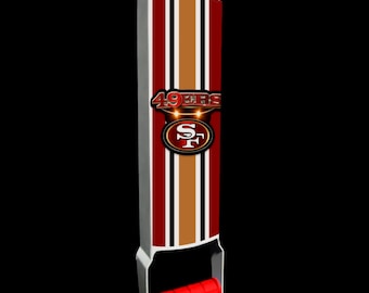 May include: A red, white and gold metal can opener with a red handle and a 49ers logo. The logo is red, gold and white with the words "49ers" in red.