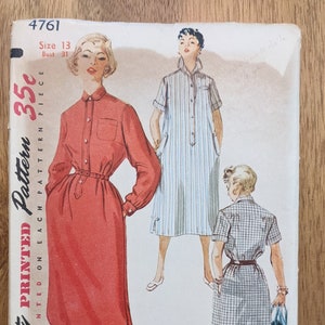 Könnte beinhalten: Vintage Simplicity Schnittmuster Nummer 4761, Größe 13, Brustumfang 31. Das Schnittmuster ist für ein Kleid mit Knopfleiste, langen Ärmeln und einem Gürtel. Das Schnittmuster enthält drei verschiedene Ansichten des Kleides, eine in Rot, eine in blau-weiß gestreiftem Stoff und eine in Karomuster.