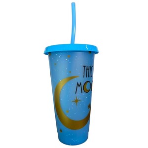 May include: A blue reusable tumbler with a gold crescent moon and stars design. The tumbler has a lid and a straw. The text "This is my moon" is printed on the tumbler.