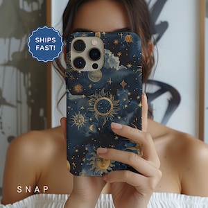May include: A phone case with a dark blue background and a gold celestial pattern. The pattern includes stars, moons, and suns. The case is designed for a phone with a camera bump.