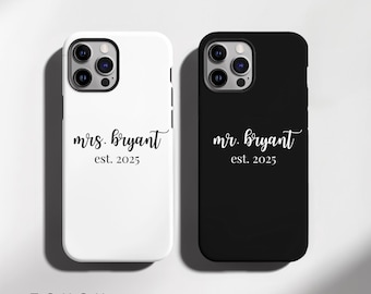 May include: Two phone cases, one white and one black, are shown. The white case has "mrs. bryant est. 2025" in a cursive font. The black case has "mr. bryant est. 2025" in a similar font. The word "TOUGH" is at the bottom.