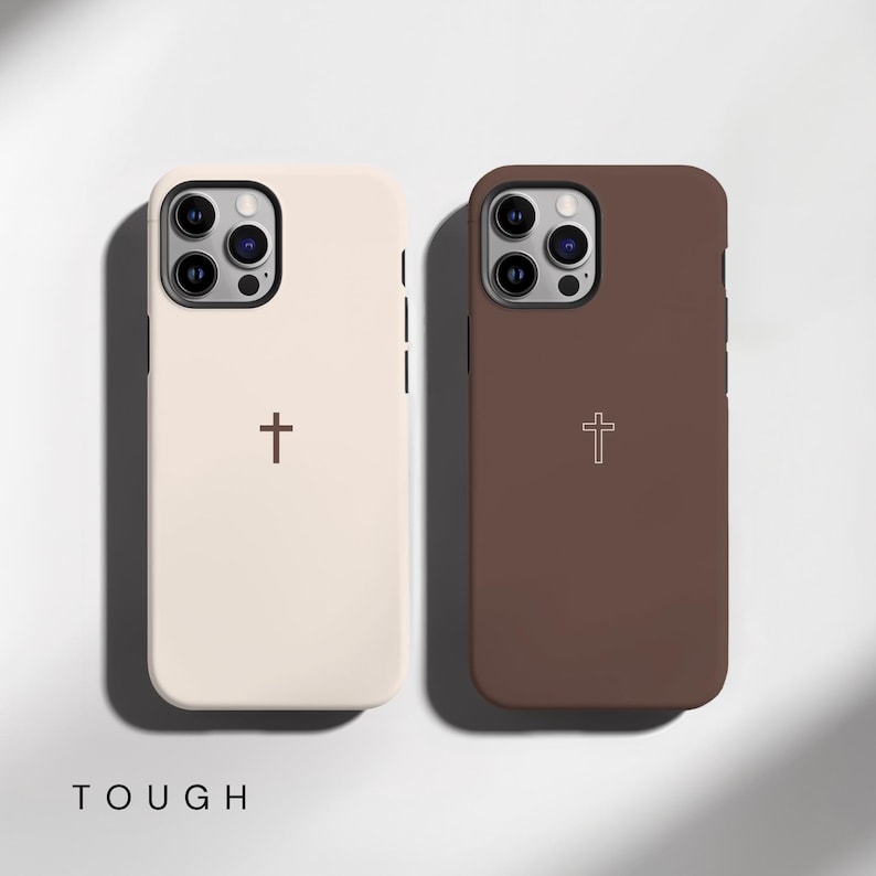 May include: Two phone cases, one cream-colored and one brown, each featuring a cross design. The word "TOUGH" is printed at the bottom. The cases have a smooth finish and are designed to protect the phone.