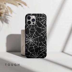 May include: Black phone case with a white spiderweb pattern.
