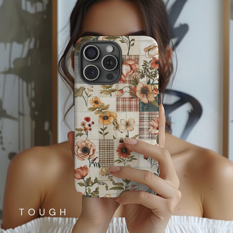 May include: A white iPhone case with a floral patchwork design. The case features a variety of flowers in shades of pink, yellow, and orange, arranged in a patchwork pattern. The case is made of durable plastic and has a clear back.
