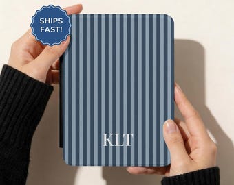 May include: A rectangular e-reader case featuring a vertical striped pattern in alternating shades of dark and light blue. The centre of the case displays the white capital letters KLT. A blue scalloped badge in the top left corner reads SHIPS FAST!