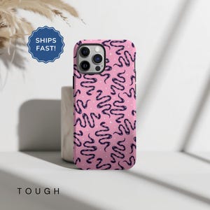 May include: A pink phone case with a pattern of black snakes and white stars. The case is designed for an iPhone with a camera bump.