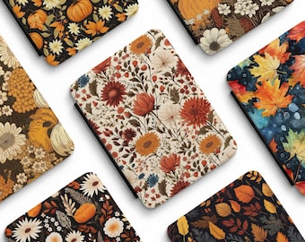 May include: A collection of rectangular e-reader cases featuring various autumn-themed patterns including orange pumpkins, white and red flowers, and colorful maple leaves. The cases display intricate botanical illustrations and seasonal foliage designs with the text Amore Cases visible.