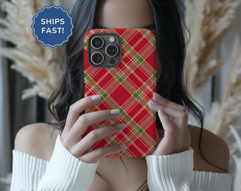 May include: A red, green and white plaid phone case for an iPhone 13 Pro Max. The case is being held up to cover the face of a person.