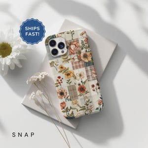 May include: A white iPhone case with a floral patchwork design. The case features a variety of flowers in shades of red, orange, yellow, and green. The background is a cream color with a subtle plaid pattern.