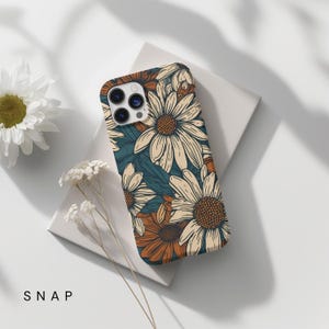May include: A phone case with a floral pattern. The case features a white background with a repeating pattern of brown and white daisies. The case is designed for an iPhone.