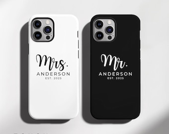 May include: Two phone cases, one white and one black, with the words "Mrs. ANDERSON EST. 2025" and "Mr. ANDERSON EST. 2025" in elegant script. The word "TOUGH" is printed at the bottom.