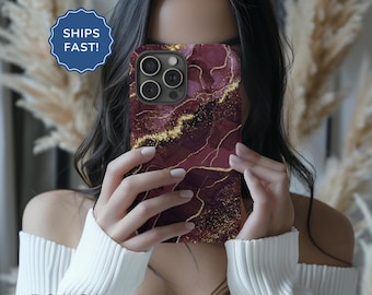 May include: A phone case with a burgundy and gold marble design. The case has a cutout for the camera lens.