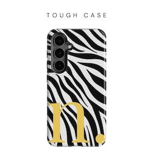 May include: A phone case with a black and white zebra print design, with the gold letter "n." and the text "TOUGH CASE" at the top. The case has a camera module on the upper left.