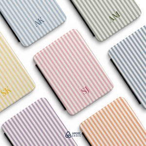 May include: A collection of rectangular tablet cases featuring vertical stripes in various pastel colors including blue, green, yellow, pink, purple, and orange. Each case displays a two-letter monogram in the center and the text AMORE CASES.