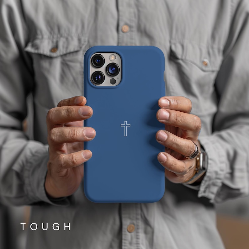 May include: A blue phone case with a white cross design. The case has a smooth texture and is designed to fit a smartphone. The word "TOUGH" is printed at the bottom of the case.