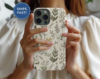 May include: A white phone case with a floral pattern featuring green leaves and small yellow flowers. The case is designed for an iPhone with a triple lens camera.