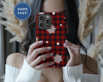 May include: A red and black checked phone case with white snowflakes and stars. The case is designed for a smartphone with a triple lens camera.