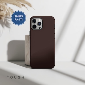 May include: A dark brown phone case with a camera lens cutout. The case is made of a durable material and is designed to protect your phone from drops and scratches.