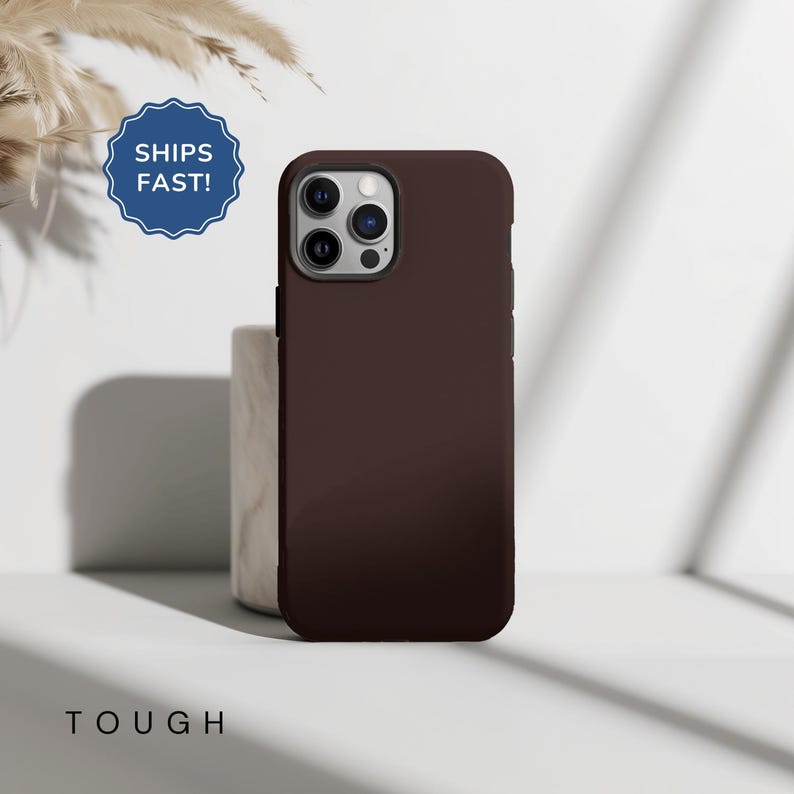 May include: A dark brown phone case with a camera lens cutout. The case is made of a durable material and is designed to protect your phone from drops and scratches.