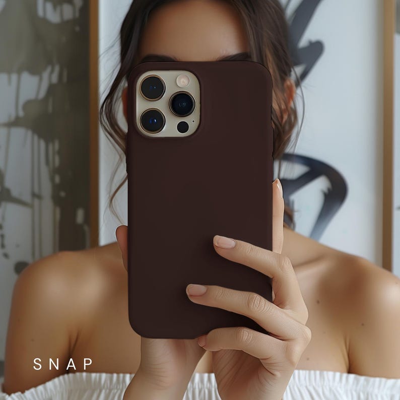 May include: A brown silicone phone case for an iPhone with a camera lens cutout. The case is smooth and has a matte finish.