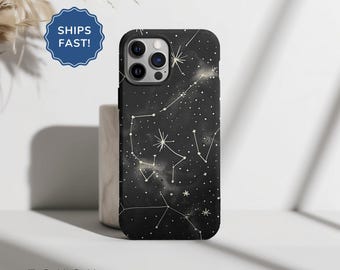 May include: Black phone case with a constellation design. The case features a dark background with white and gold star patterns and the word "TOUGH" at the bottom. The case is shown standing upright.