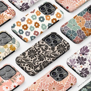 Pu&ograve; includere: Una collezione di custodie per telefoni con disegni floreali in vari colori, tra cui arancione, rosa, marrone e blu. Le custodie presentano diversi motivi floreali, con un mix di margherite e motivi floreali astratti. Disposte ad angolo.
