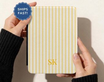 May include: A rectangular e-reader case featuring a vertical yellow and white striped pattern. The centre of the case is personalised with the yellow capital letters SK. A blue circular badge in the upper left corner displays the text SHIPS FAST.