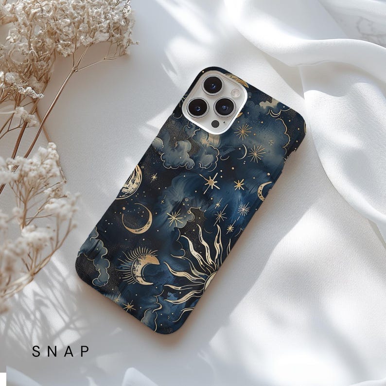 Puede incluir: Una funda de tel&eacute;fono azul con un dise&ntilde;o celestial que presenta estrellas doradas, lunas y un sol. La funda tiene un efecto acuarela y un fondo azul oscuro.