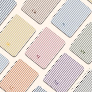 May include: A collection of striped phone cases in various pastel colors, including pink, yellow, and blue. Each case features a unique initial in a matching color. The cases are arranged in a repeating pattern.
