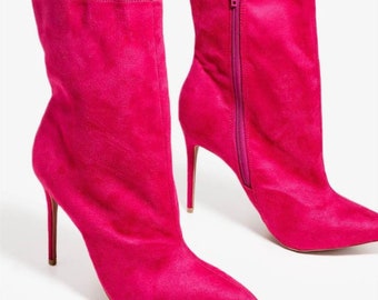 May include: A pair of vibrant fuchsia ankle boots. These stylish boots feature a pointed toe, a stiletto heel, and a side zipper. The text "Size 7" is visible at the top of the image. These boots are a bold fashion statement.