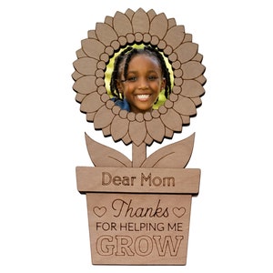 May include: A wooden sunflower photo frame with a brown pot and the text "Dear Mom Thanks for helping me GROW" in a white background.